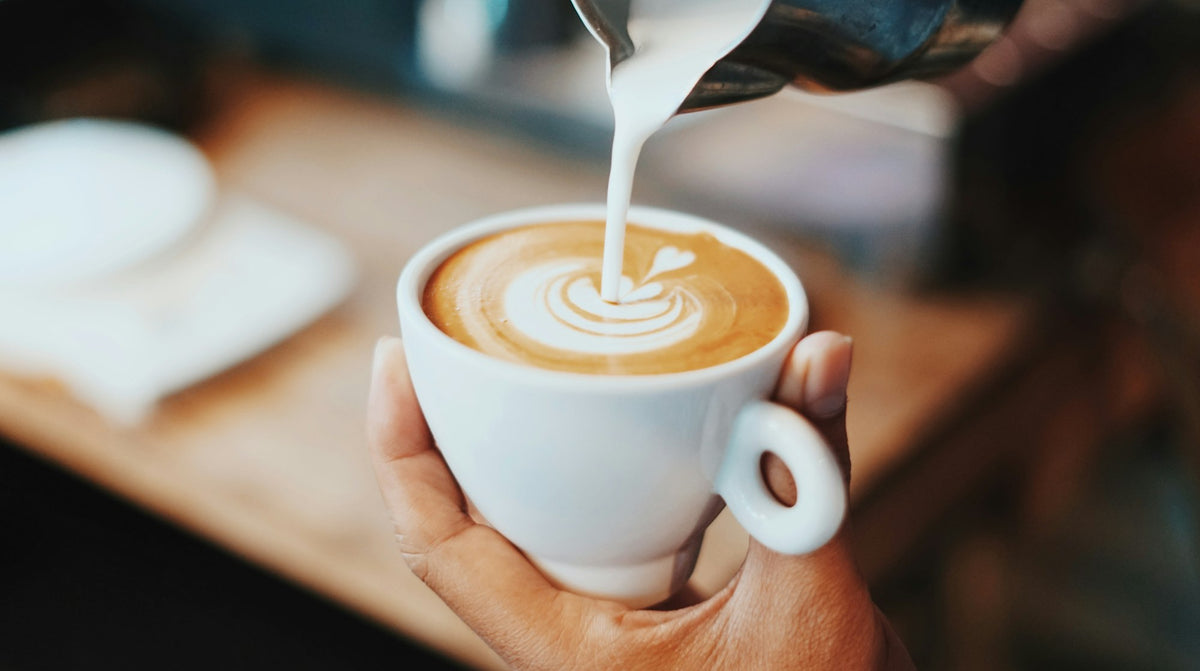 Barista pouring milk into a latte